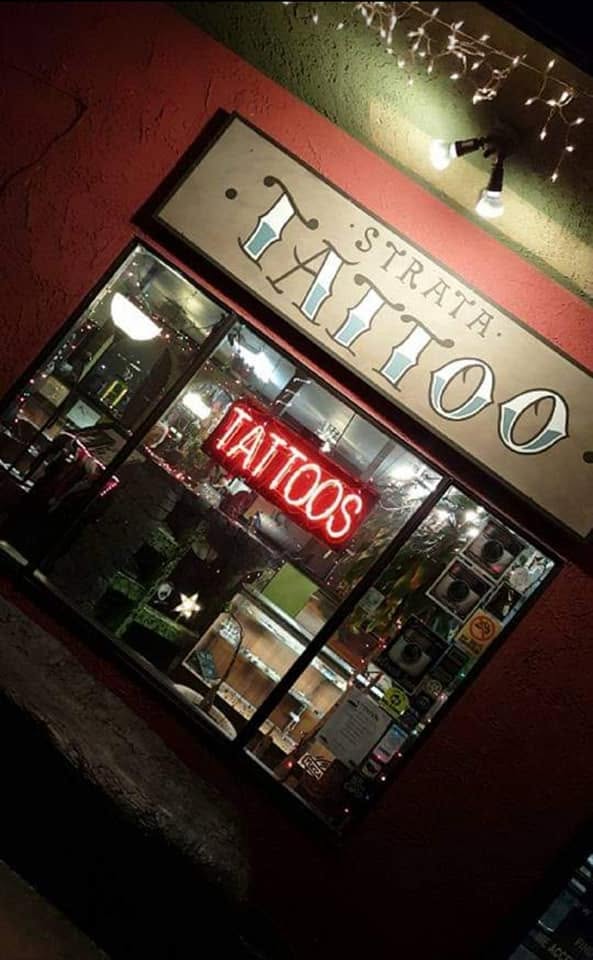 Strata Tattoo storefront and neon sign at night