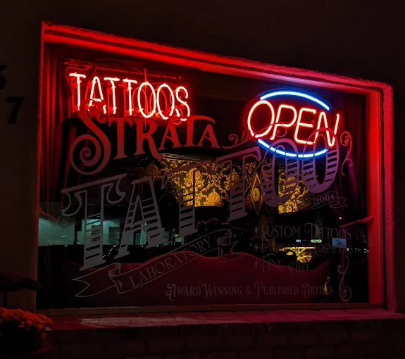 Strata Tattoo Lab neon window at night